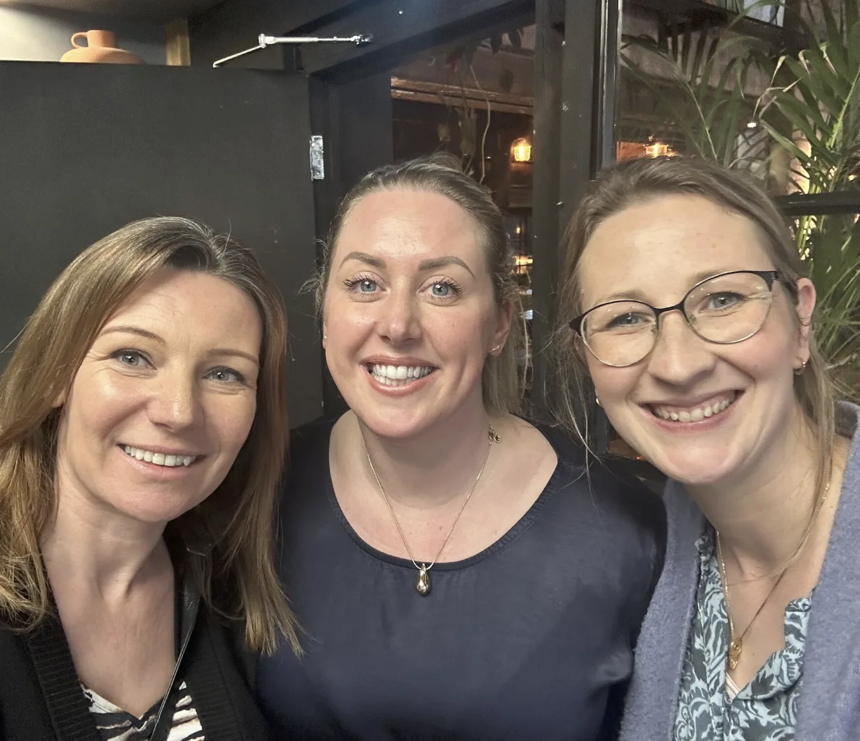 Three Strategic Circle members laughing together at an evening social
